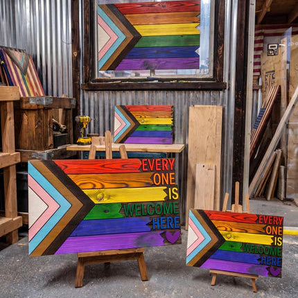 Colorful wooden art pieces with a message of inclusivity in a workshop setting.